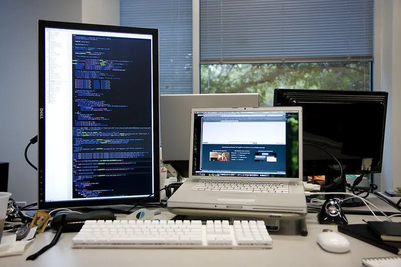 Un bureau avec un ordinateur portable et un écran en mode portrait qui
affiche du code source